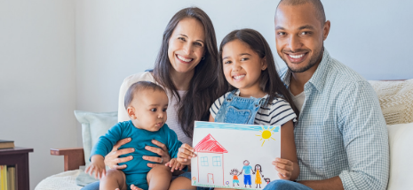 Photo of a blended family seated on a couch holding up a crayon-drawn photo